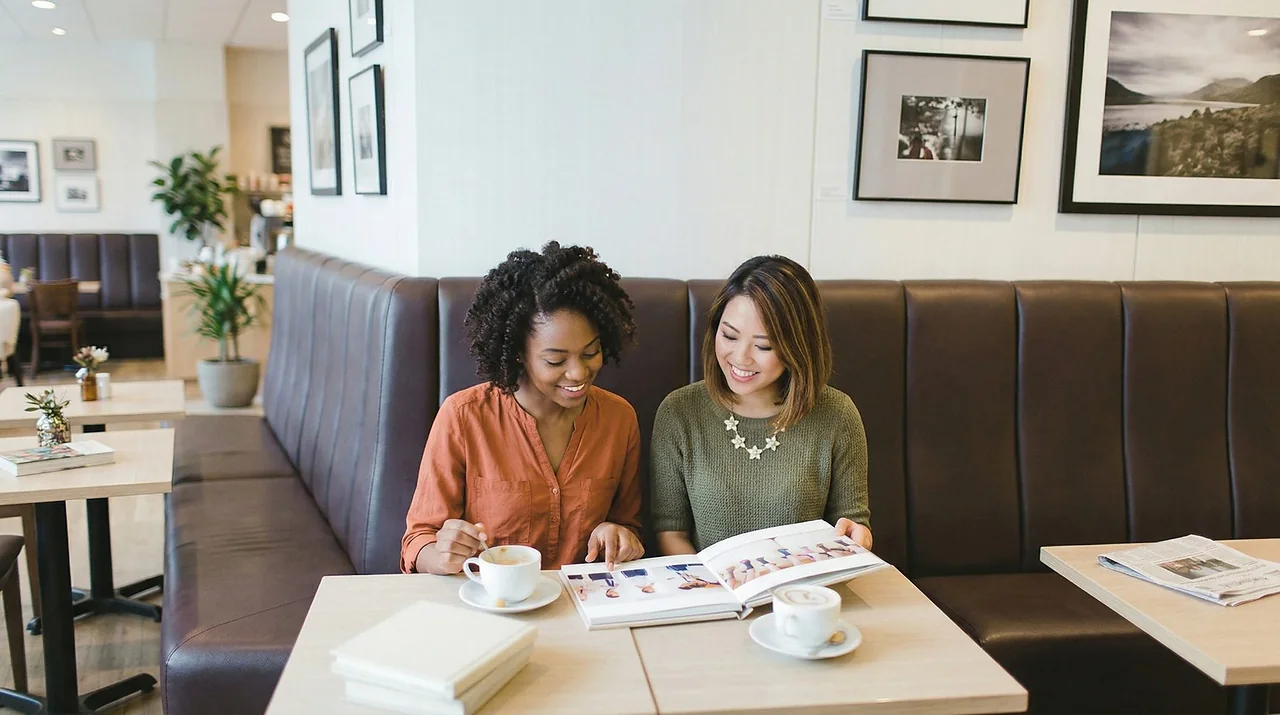 Two people at a café table looking through an open album together