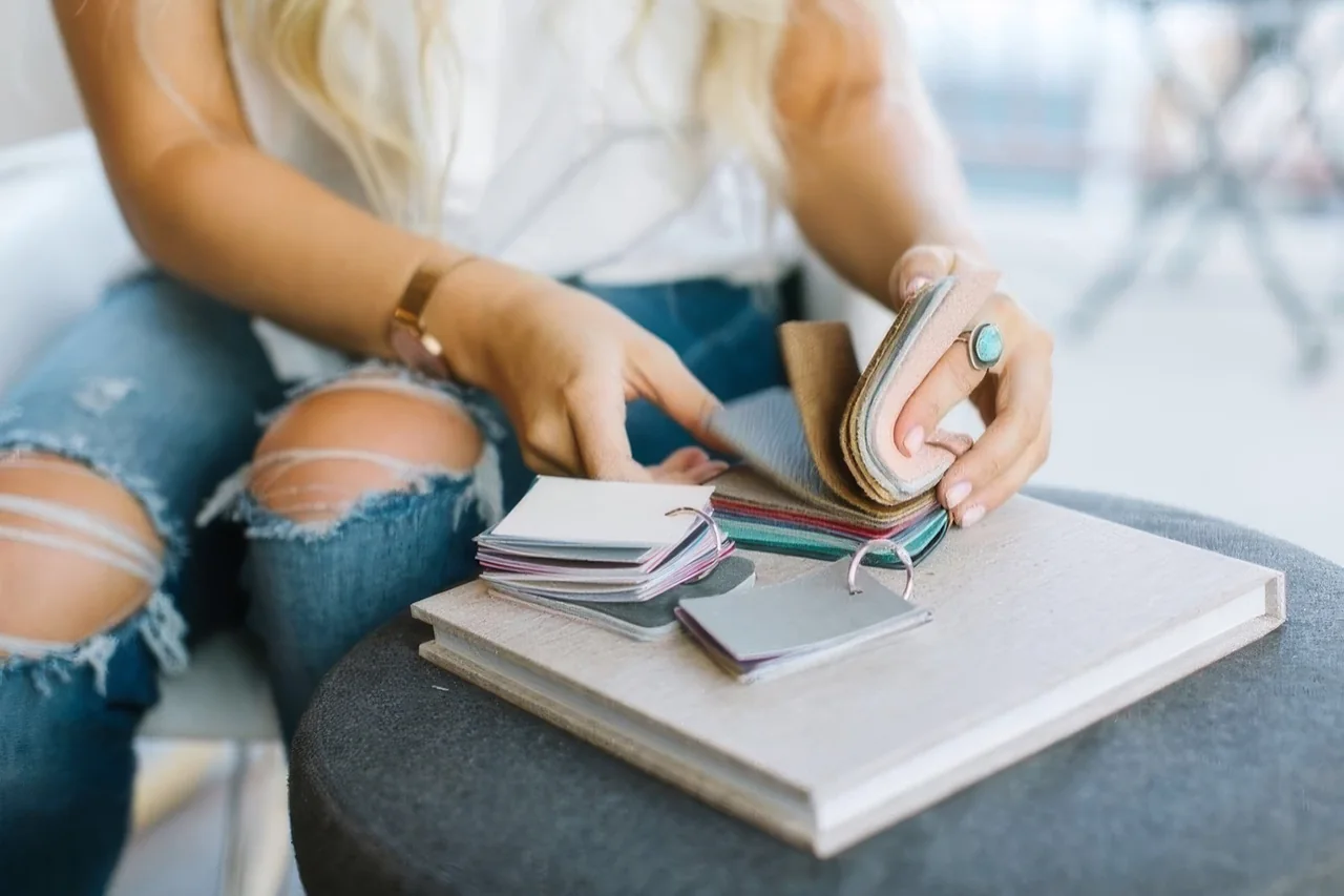 Hands leafing through a fan of linen and leather cover swatches