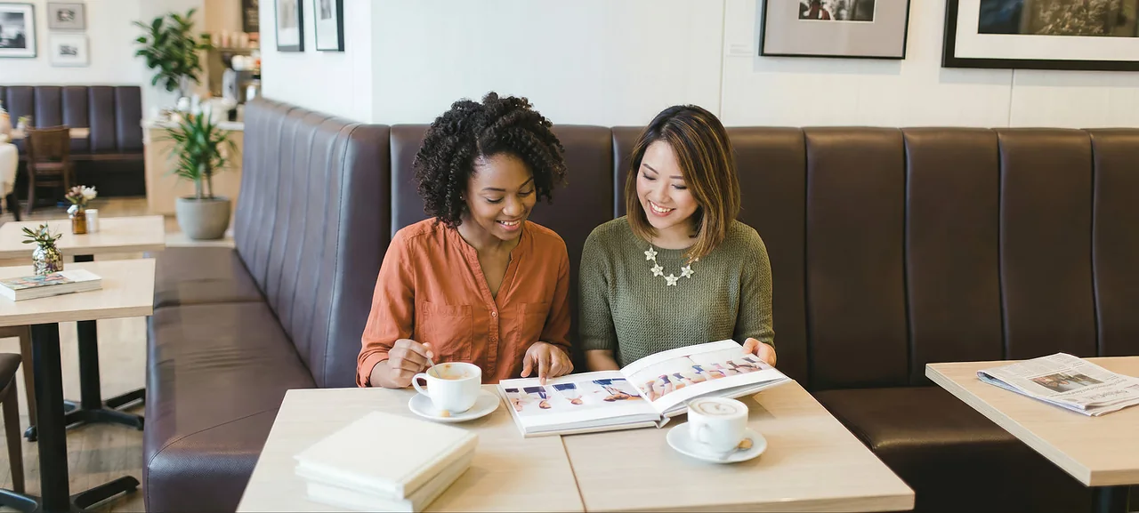 Two people sitting together with an open linen-bound book across their knees