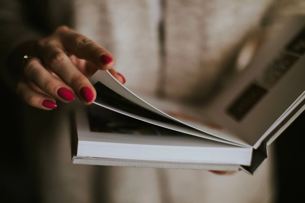 A hand turning the pages of a bound album