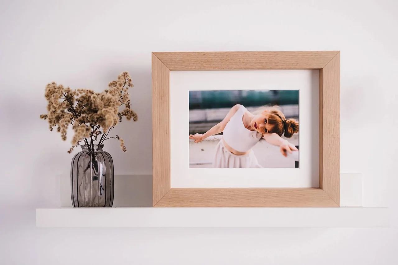 An oak frame with a matted photograph resting on a picture ledge
