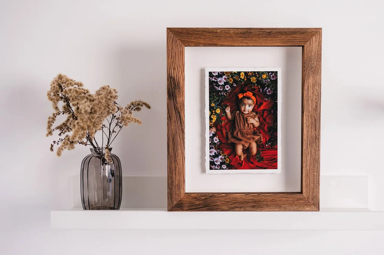 A dark wood frame with a matted photograph hanging above a shelf